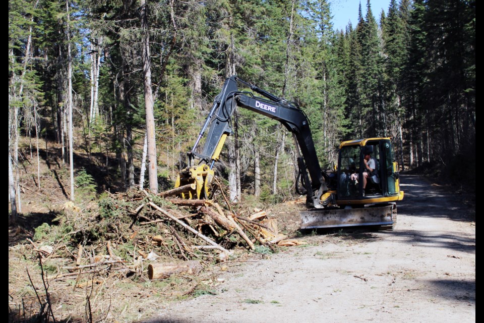 A mini-excavator piles slash left behind from logging project to reduce fire risk at Pidherny Recreation Site.