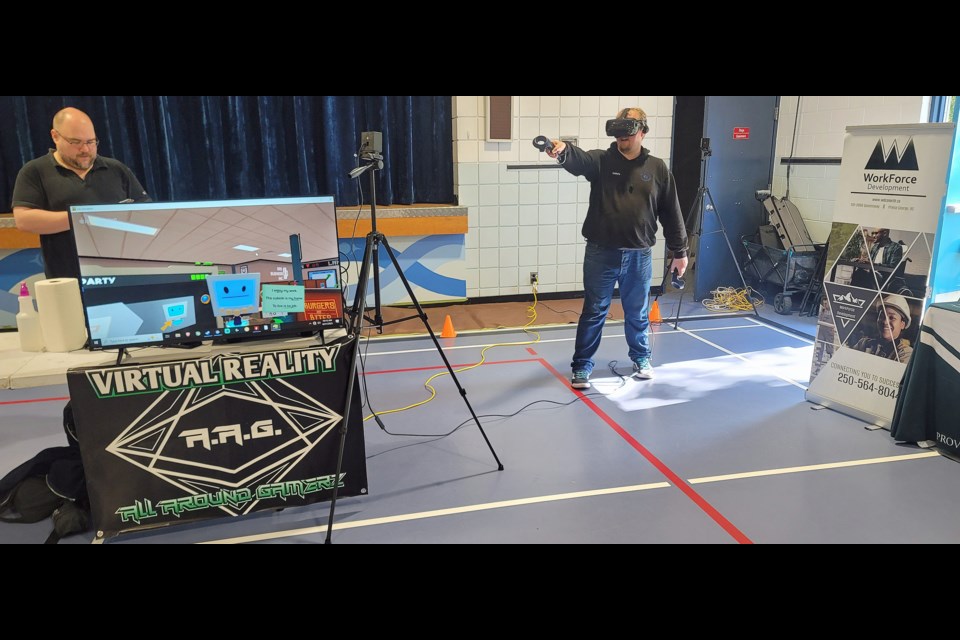 James Mills explores the world of virtual reality wearing a headset that simulates an office workplace. The VR demonstration was sponsored by Josh Croxen of All-Around Gamerz, who connected with potential employees for his Victoria Street store during the job fair at École Franco-Nord on Wednesday, Aug. 27, 2025.