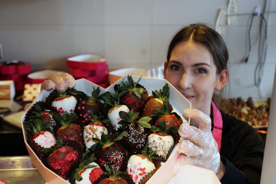 Tiffany Lamoureux shows off one of the Valentine's Day assortments of chocolate-dipped strawberries that were hot sellers Wednesday at the Rocky Mountain Chocolate Factory store Spruceland Mall. 