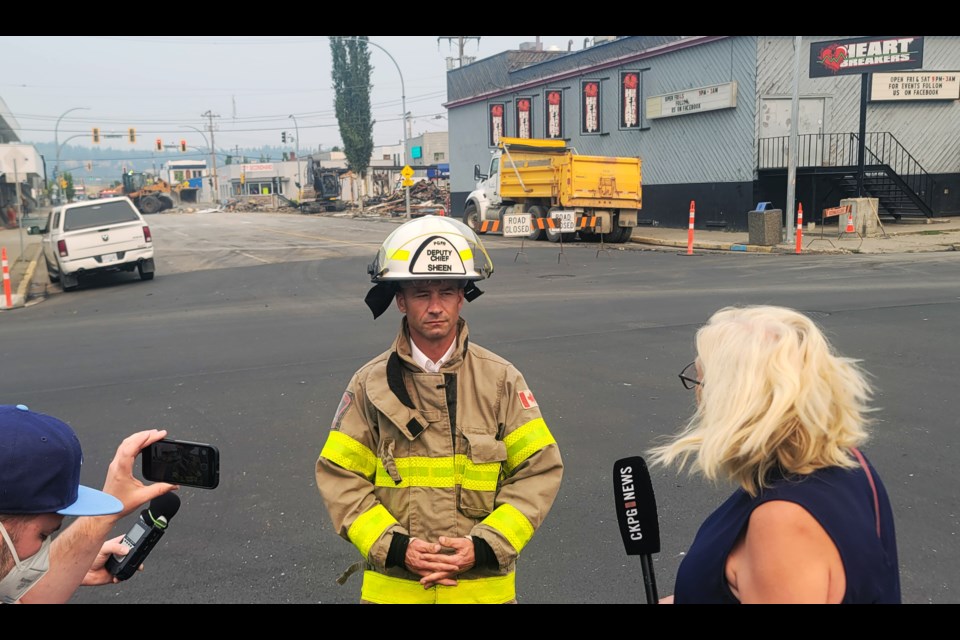 Prince George Fire Rescue deputy chief Clay Sheen addresses the media Tuesday afternoon while city crews in the background work to clear the debris after an explosion demolished the building at 422 Dominion St. 