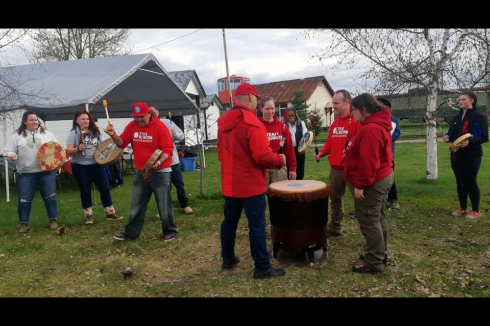 Team Rubicon members from Canada and the U.S. gathered in Prince George Saturday for a six-day disaster relief training camp join the UHNBC Traditional Drummers, led by Wesley Mitchell, left, in a pre-meal ceremony Saturday at the Central B.C. Railway and Forestry Museum.