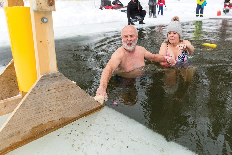 Citizen Photo by James Doyle. Mark and Carol Stofer enter the icy waters of Ness Lake on Saturday afternoon during Ness Lake Bible Camp's 21st Annual Polar Bear Dip.