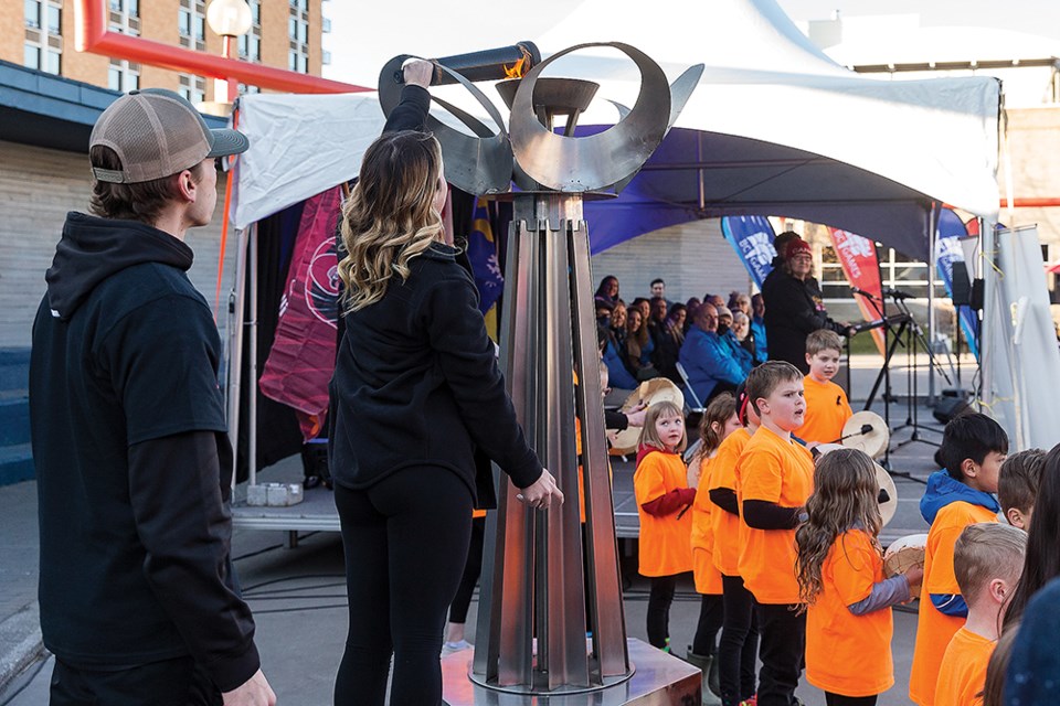 Citizen Photo by James Doyle. Alyson Emberley lights the torch as Cody Bailey, left, looks on during the Ignite the Spirit Torchlighting Ceremony on Thursday evening at Canada Games Plaza to mark 100 days until the start of the B.C. Summer Games in Prince George.