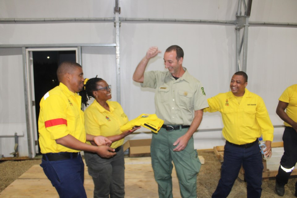 South African firefighters present a uniform to Steven Goldman, incident commander for the U.S. Forest Service, after their two-week deployment to fight wildfires west of Prince George ended on Thursday.