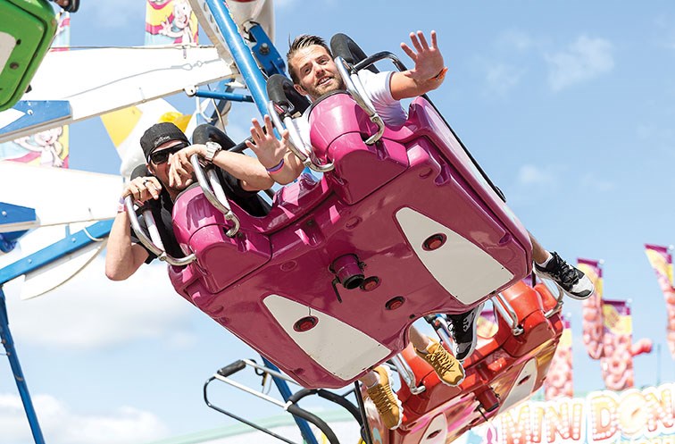 Riders on the Kiteflyer wave to the camera at the 2019 midway during the 107th BCNE. 