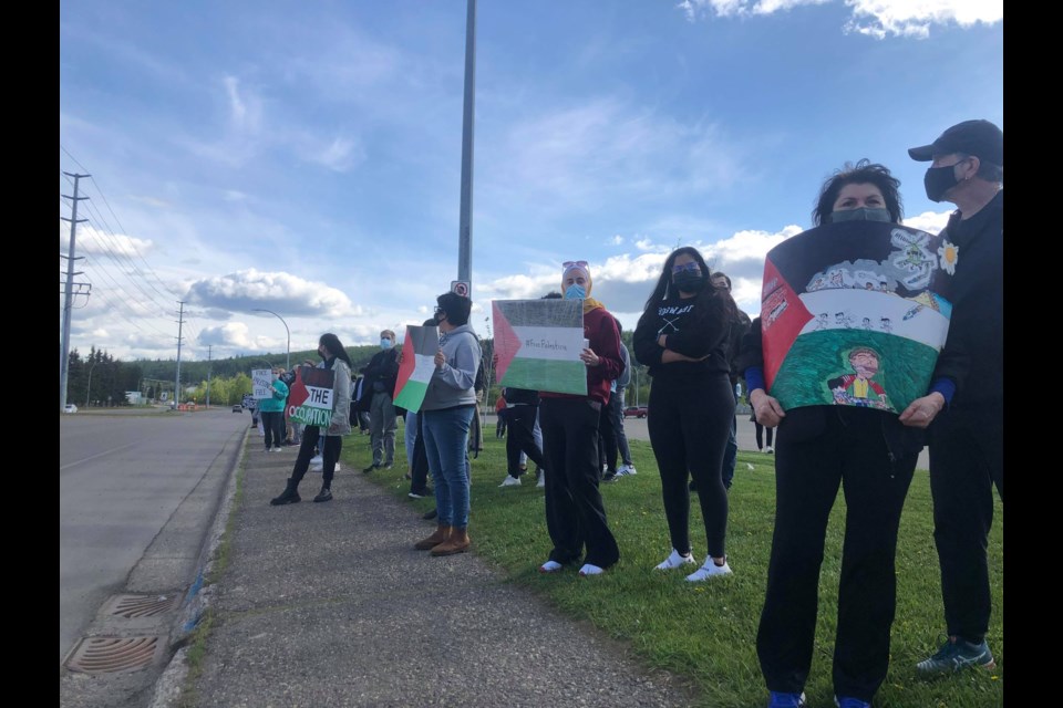 The crowd stood on Ospika Blvd to wave signs and flags at passing vehicles. 