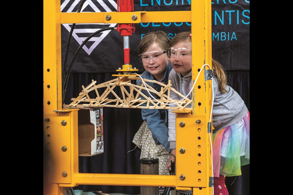 Twins Fae (left) and Ada Young, 7, pump the pressure up on the testing machine together as they watch their bridge being pushed to its limit. Their bridge reached 33.8 lbs of pressure before failure occurred while taking part in the primary division of the 26th Annual Popsicle Stick Bridge Building Contest at Pine Centre Mall Saturday.