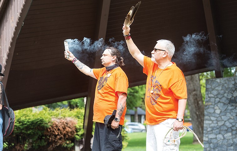 Citizen Photo by James Doyle/Local Journalism Initiative. Wesley Mitchell, left, and Ivan Paquette, right, stand on stage during an opening prayer on Saturday afternoon at Lheidli T'enneh Memorial Park during a gathering in remembrance of the 215 children whose remains were found in a mass grave on the site of a former residential school in Kamloops.