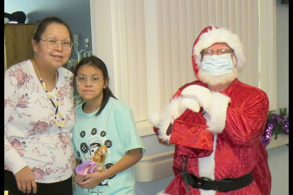 Karissa Wright, along with her eldest daughter Michayla, take a moment to pose with Santa who brought toys to the children at UHNBC Friday morning.