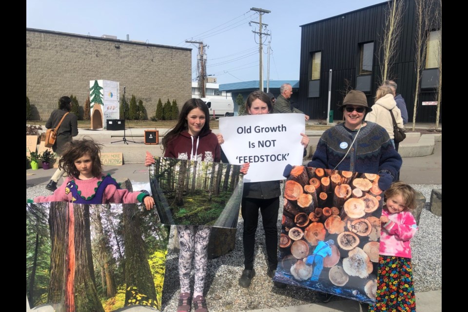 A family holds signs while attending the Rebellion for Forests Rally in downtown Prince George. 