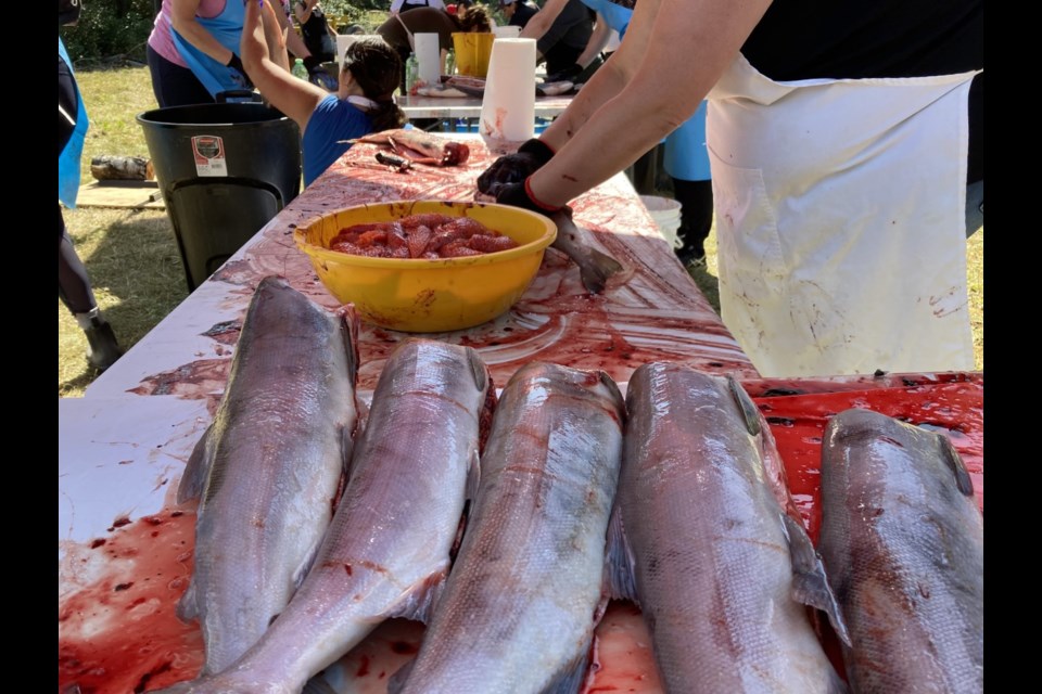 An assembly line of workers prepares the salmon.