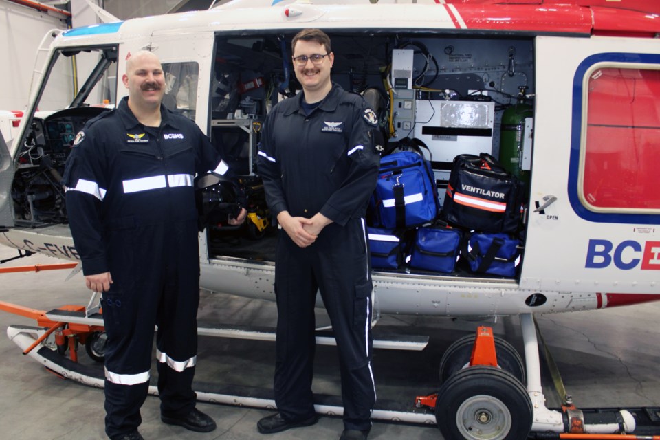 BCEHS helicopter flight paramedics Brian McNamara, left, and Cole Shaver stand in front of the Bell 412 helicopter that takes them to sick and injured patients all over north central B.C.