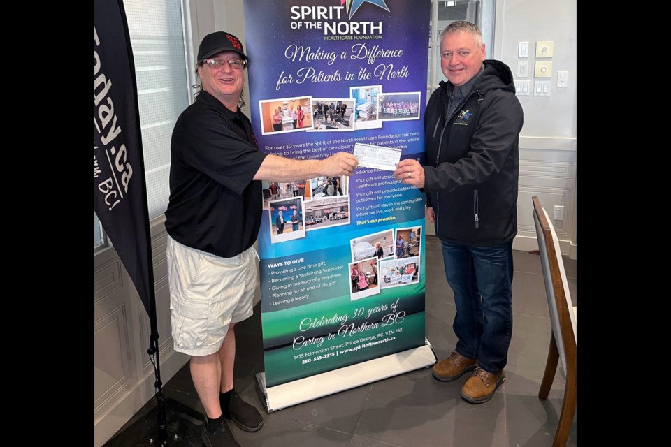 Cam Thun, left, hands a $25,000 cheque to Darcy Bryant, president of the Spirit of the North Healthcare Foundation, during the Spirit Day fundraiser on Thursday.