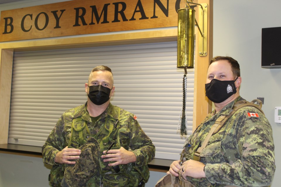 Rocky Mountain Rangers Corporals Rob Pears and Eamon McArthur with a bell on which the members who first joined the infantry reserve when it was established in Prince George in 2011. Their names are on the bell. 