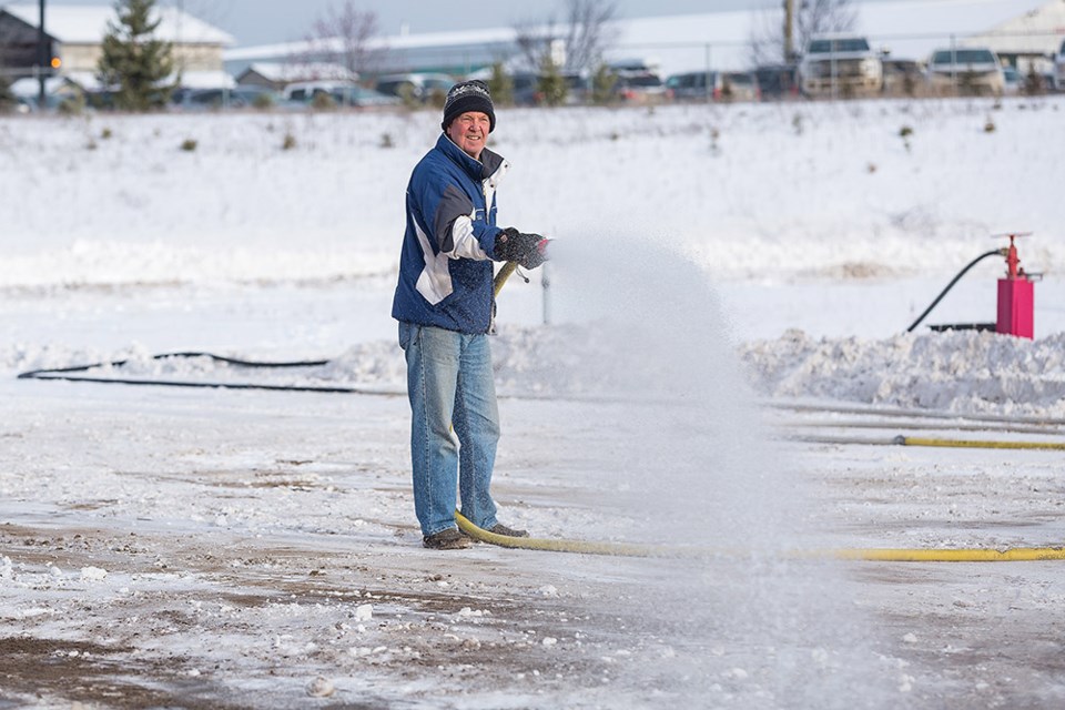 Volunteer Gerry Van Caeseele uses a hose on Sunday morning during the building of the ice surface at the Prince George Outdoor Ice Oval.