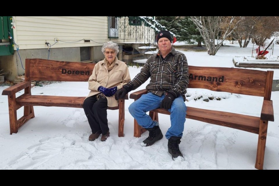 Doreen Denicola and her son, Drew Larson, sit on the benches created from the tree that reflected the family's legacy on their Prince George homestead.
