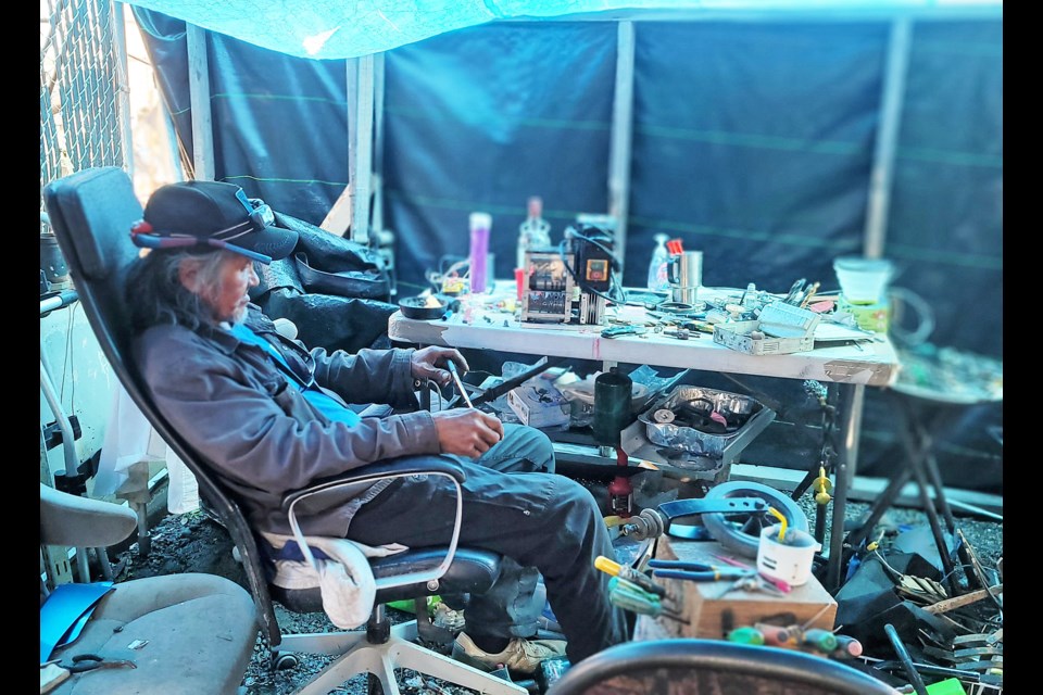 Bel Johnny, a five-year resident of the Moccasin Flats encampment in downtown Prince George, works on piecing together a cart wheel to help a neighbour who uses the cart to haul water to her shelter space at the camp.