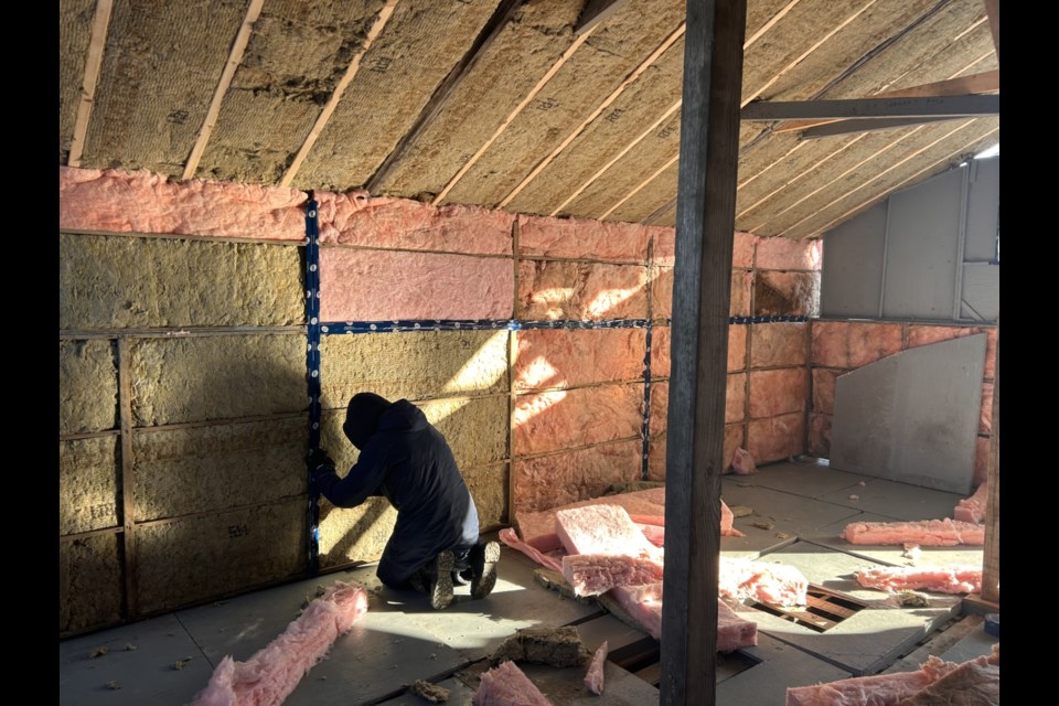 A volunteer works on insulating the bunkhouse. 