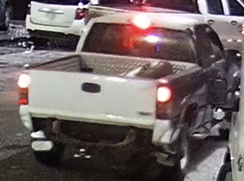 older model Chevrolet truck. The driver’s side of the vehicle is red and the passenger side is black, and there are blue or black racing stripes down the hood of the vehicle.