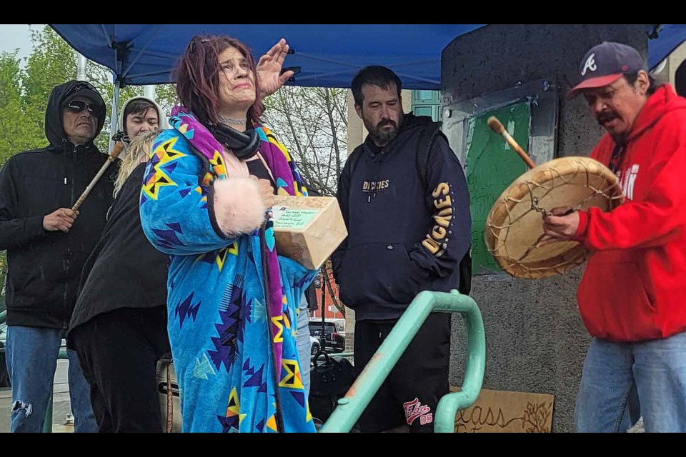 Tamara Hayden, centre, the daughter of Hank Hayden, looks up as the sun tries to peek through the clouds on a showery afternoon on Wednesday, May 14, 2025 during the Healing Fire tribute to Hank, the 'Mayor of Moccasin Flats,' who died at the homeless encampment Dec. 8.