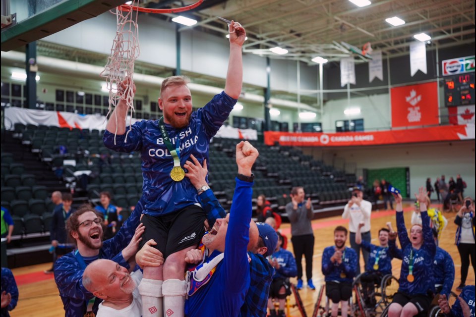 Team BC captain Joel Ewert cuts down the net while being held high by his coaches and teammates after he helped B.C. win gold in wheelchair basketball at the Canada Winter Games in Charlottetown, P.E.I.