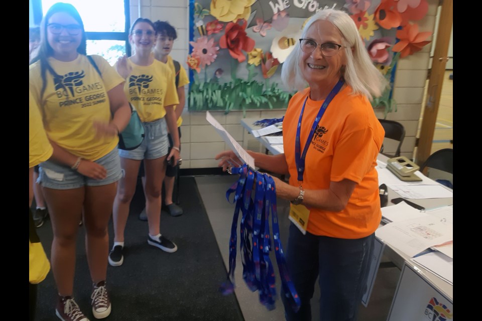 Sporting her bright orange T-shirt as a volunteer for the 2022 BC Summer Games, Nelda McInnis  greets the Kootenays zone swimming team Wednesday afternoon. They will be staying overnight at Foothills Elementary School for the next four days while they compete in the Games..