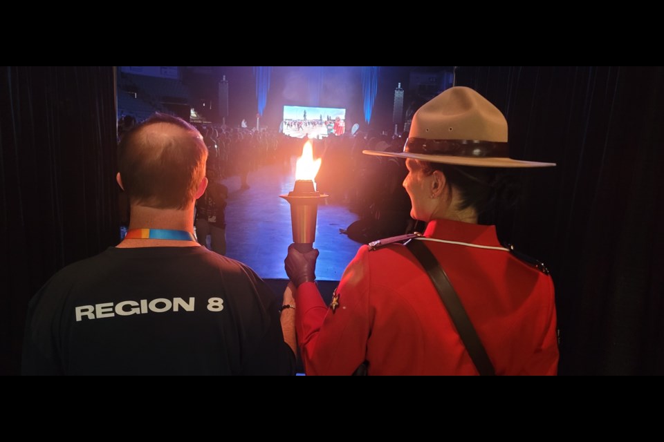 Prince George Special Olympics 10-pin bowler Greg Cole, left, and RCMP Cpl. Jennifer Cooper carry the torch into the crowd at CN Centre at the opening ceremony of the Special Olympics BC Summer Games on Thursday, July 10, 2025.