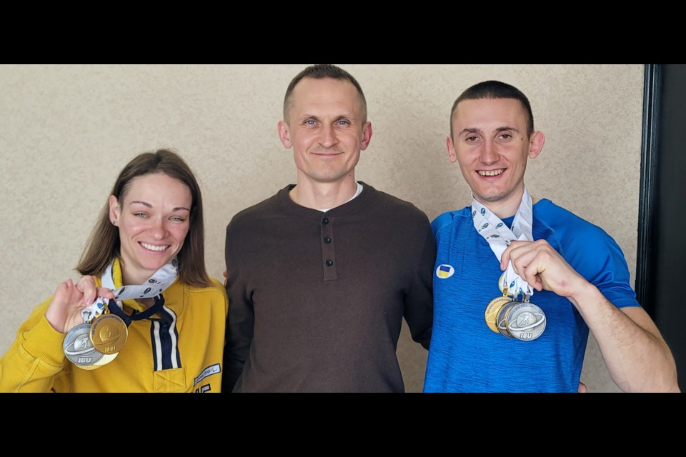 Liudmyla Liashenko, left, and Taras Rad, right hold the Para Biathlon World Championships medals with Ukrainian interpreter Olexii Miroshynk.