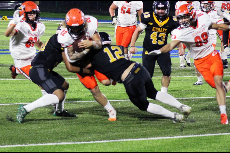 Okanagan Sun running back Aiden Wieberg gets tackled by Kodiaks defensive back Hayden Matheson (12) and Shandon Donovan, left, in Saturday's BCFC game at Masich PLace Stadium.