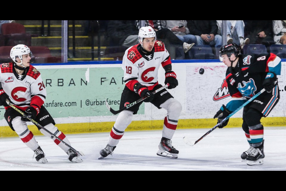 Keaton Dowhaniuk, left, and Borya Valis of the Cougars watch the puck with Kelowna Rockets defenceman Marek Rocak during Game 4 WHL playoff action Wednesday in Kelowna.