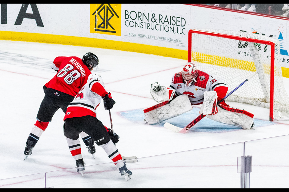 Portland WInterhawks forward Alex Weiermair scores his third goal of the game on Prince George Cougars goalie Josh Ravensbergen while being checked by defenceman Carson Carels Tuesday, April 1, 2025 in Portland, Ore.