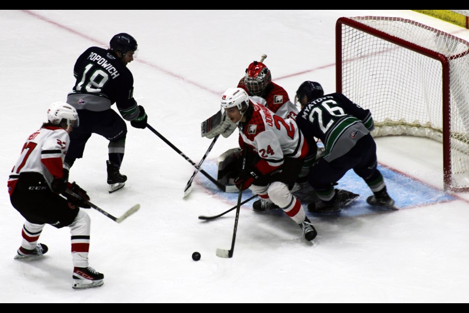 Keaton Dowhaniuk clears the puck while Seattle Thunderbirds winger Nico Myatovic draws a crowd of Cougars in the crease during second-period action Wednesday in Game 4 at CN Centre.