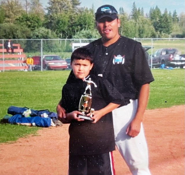Joey Potskin and his son Tre hold up one of the trophies Joey won during his time as one of the city's best-ever fastball  players.
