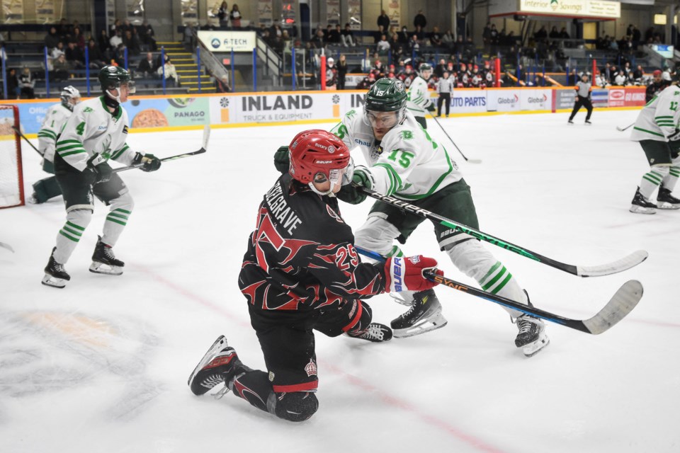 Spruce Kings winger Carter Hesselgrave gets down on one knee to make a pass back to a teammate while being checked by Cranbrook Bucks defenceman Sam Belanger Friday at Kopar Memorial Arena. The Bucks won the game 7-4. 