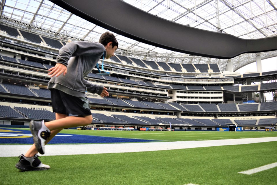 Ethan sprints the length of the football field at SoFi as part of a stadium tour.