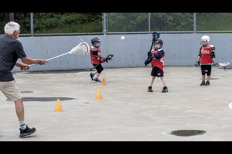 Lifelong lacrosse player and coach Tony Ciolfitto tosses a ball to Alexander Moore, 7, to see how he handles his stick at a U-9 PG Posse lacrosse practice at the Carney Street lacrosse box Wednesday evening.