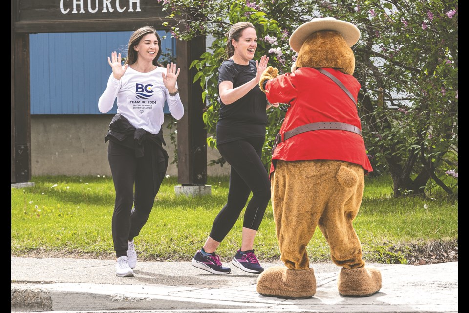 Safety Bear welcomes Melissa Lang (front) and Michelle Cruickshank as they cross the finish of the 2024 Law Enforcement Torch Run at Fifth avenue and Victoria StreetThursday. Cruickshank is Vice President, Sport & Program for Special Olympics BC, the charity the Torch Run benefits. she was in town dealing with details for the 2025 Special Olympics BC Summer Games which are to be held in Prince George July 10-13 next year, with over 1,100 athletes participating.