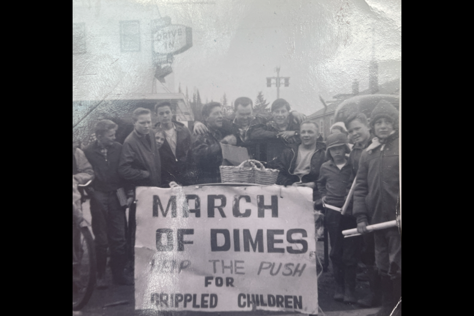 Karl Weisbrod, Jim Smith, Ian Wallin and Bud Prockiw — the four men at centre — celebrate their arrival at CKPG's Third Avenue studio after pushing a hospital bed from Vanderhoof to Prince George for the March of Dimes on Saturday, March 30, 1963. Their basket of donations can be seen atop the bed.