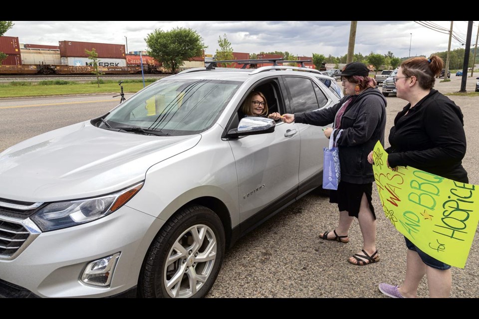 Shirley Bond pulls up to CSN Collision Norgate Sunday, June 1, 2025 and hands over a donation to Charlie and Alicia Fitzpatrick to get her car washed in their fundraiser for Hospice. This is the sixth year the business has run a car wash and barbecue to raise money for the palliative care society.