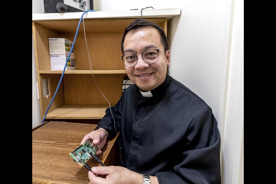 Father Rector holds the computer that generates and controls the electronic bell tones that are broadcast through a public address system and speakers to produce the bell tones heard from the Sacred Heart Cathedral bell tower Wednesday, April 30, 2025.