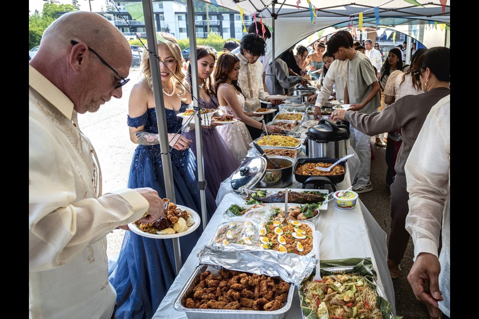 Participants in the Santacruzan Parade were the first to partake in the potluck feast in the Sacred Heart School yard Sunday, June 22, 2025.