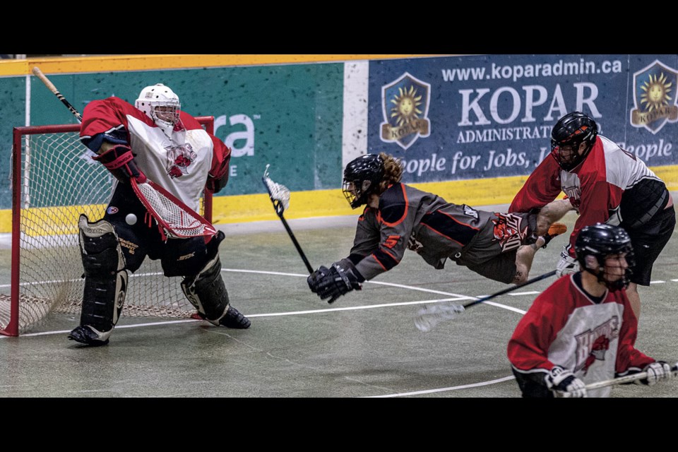 BHL/X-Conditioning Bandits goalie Liam Miller blocks a shot loosed by Scamp Transport Devils Danton Nicholson as he flies through the air propelled by Bandits' Dusty Cathcart Thursday night at Kopar Memorial Arena. Devils won the first of their best of three semi-final match 13-4. 