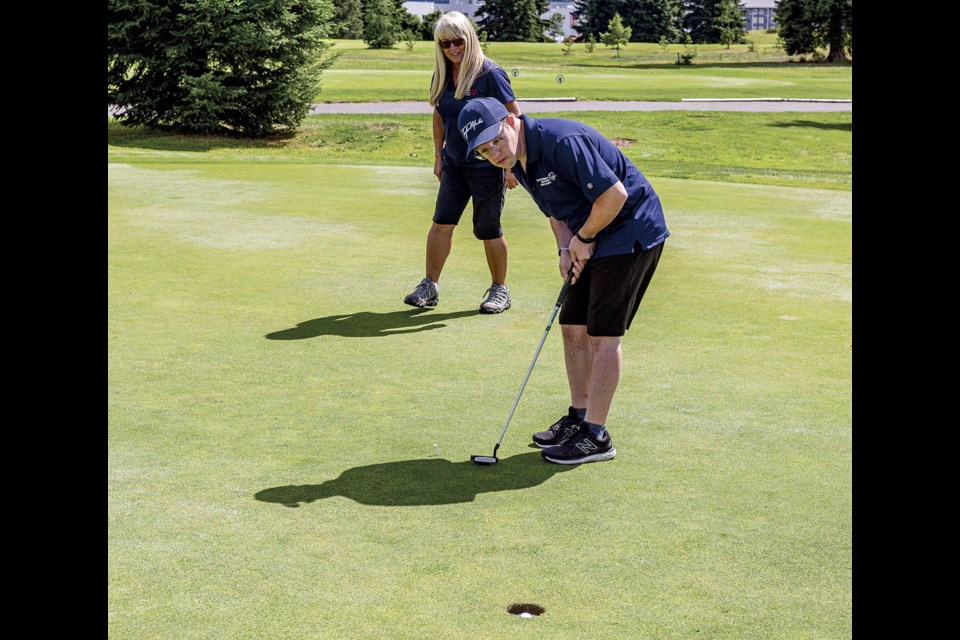Special Olympics PG head golf coach Fern Russell smiles as athlete Greg Cole sinks a putt on the ninth hole for a donation from the foursome playing the hole during the 2025 fundraising tournament at PG Golf and Curling Club Friday, July 25, 2025.