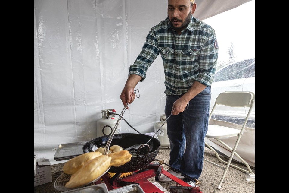 Jatinder Singh, owner of Dana Mandi Indian Restaurant, prepares fried bread balls at his tent during the Vaisakhi Nagar Kirtan at CN Centre Saturday, May 17, 2025.