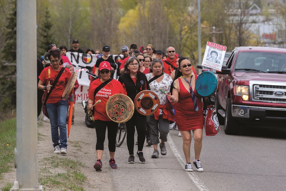 About 70 people, accompanied by the UNHBC Drummers, make their way from the House of Ancestors along Highway 16 West to the Red Dress Memorial at Ferry Avenue on Sunday, May 5, 2024 in Prince George, B.C. The walk was held to commemorate the National Day of Awareness for Missing and Murdered Indigenous Women and Girls. 