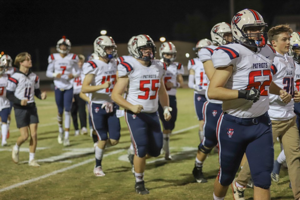 The American Leadership Academy-Queen Creek football team heads onto the field in last season’s playoff game against Hamilton. The Patriots were placed in the open division for playoffs, as they were a top-10 team in Arizona last season.