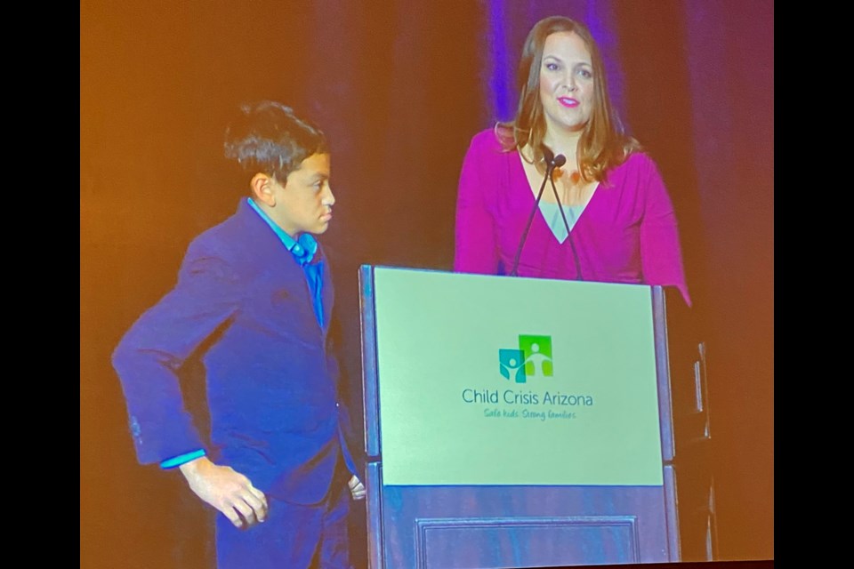 Lea Phillips, a Child Crisis Arizona board member, speaks at the Oct. 1 Brunch for Love fundraising event with her foster son by her side.