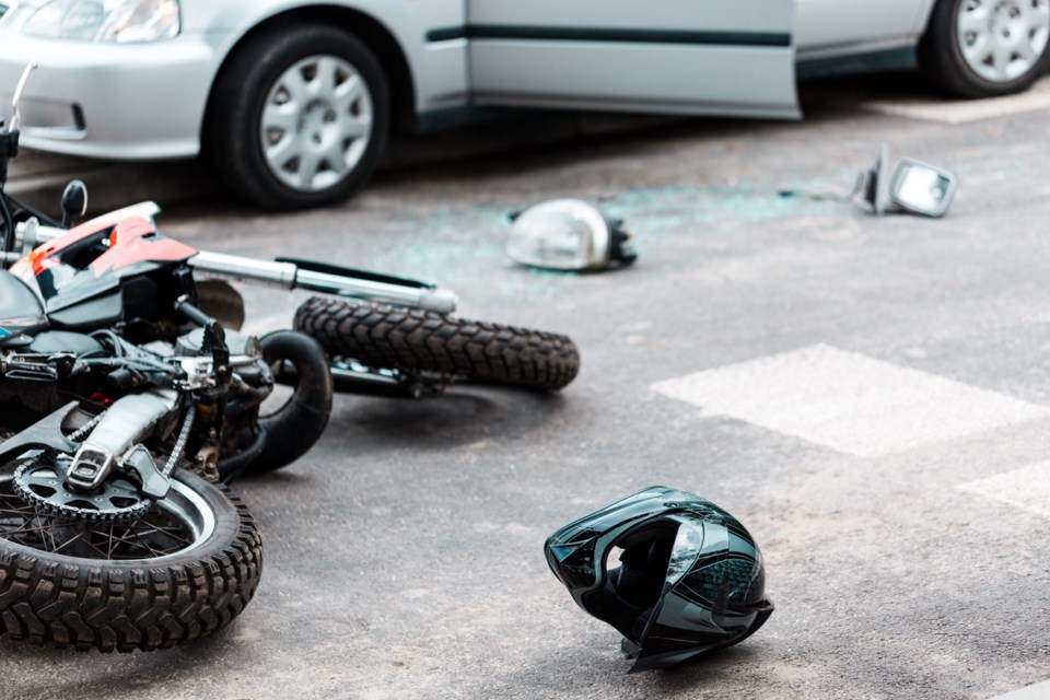 Overturned motorcycle and helmet on the street after collision with a car.