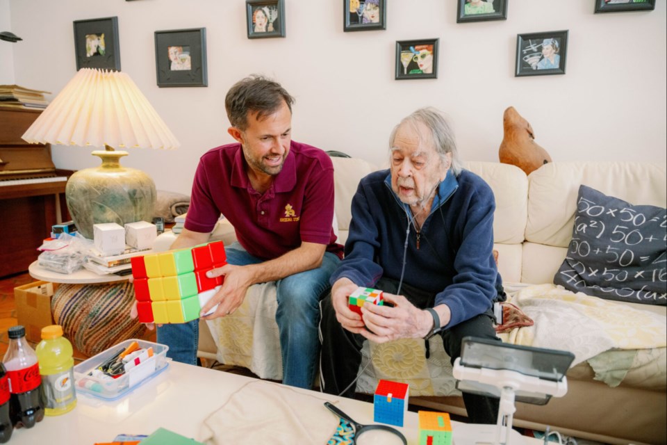 Math professor JW Gaberdiel listens to Dr. Evar Nering explain his formula for solving the Rubik’s Cube.