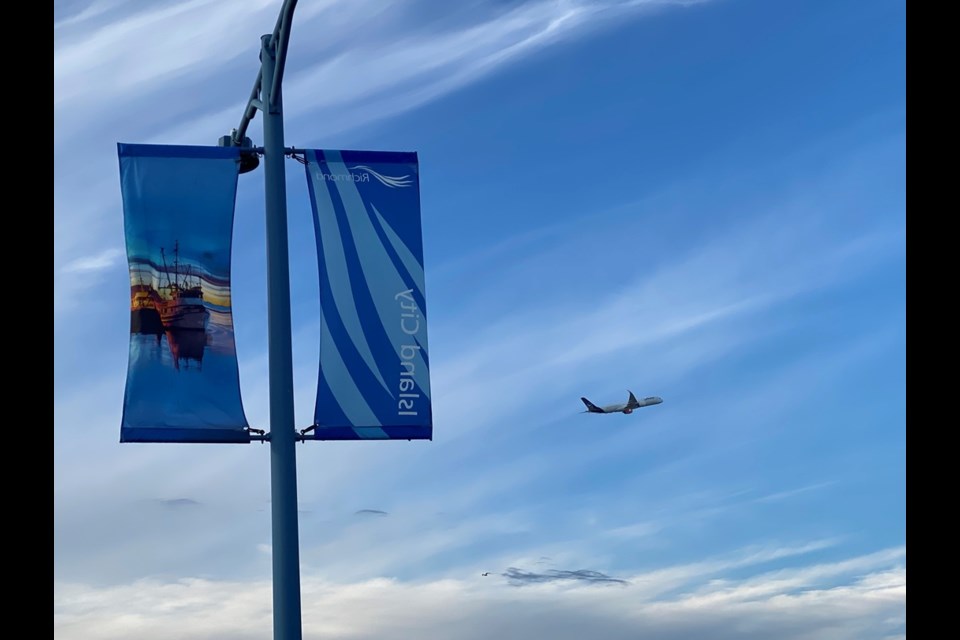 A plane takes off in the background next to the Island City banner in Richmond.
